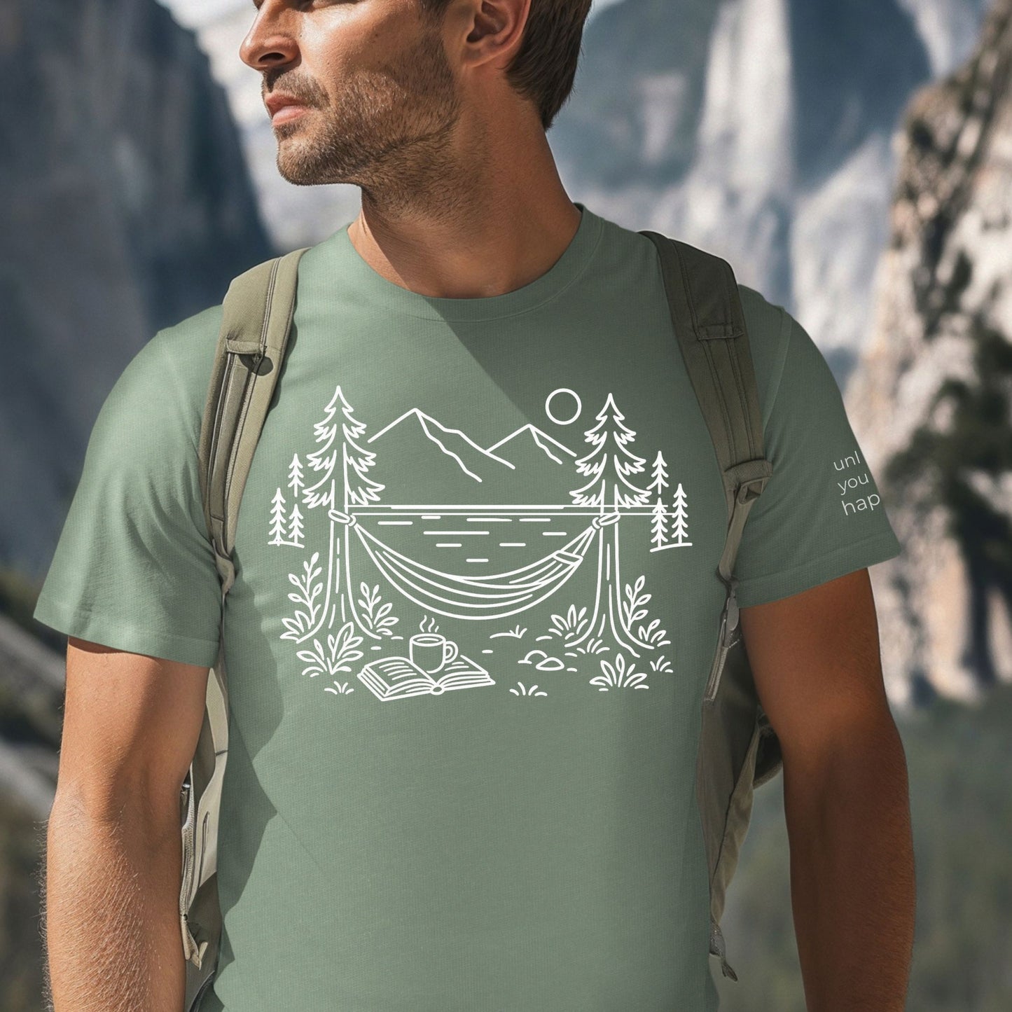 Sage  unisex t-shirt with a white line art hammock scene featuring mountains, trees, a lake, coffee cup, and open book, plus ‘unlock your happy’ on the sleeve on a male.