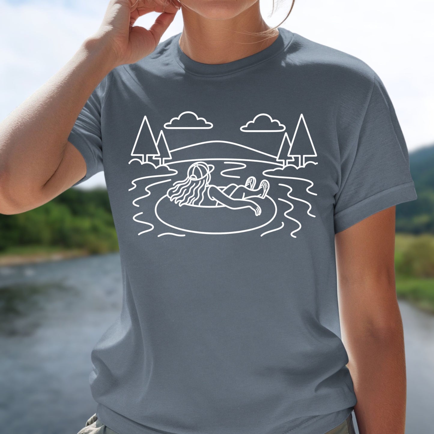 River tubing graphic blue t-shirt with minimalist outdoor water and tree line art design on female