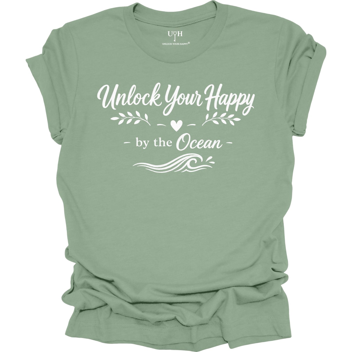 Sage-green t-shirt with 'Unlock Your Happy by the Ocean' text on a white background
