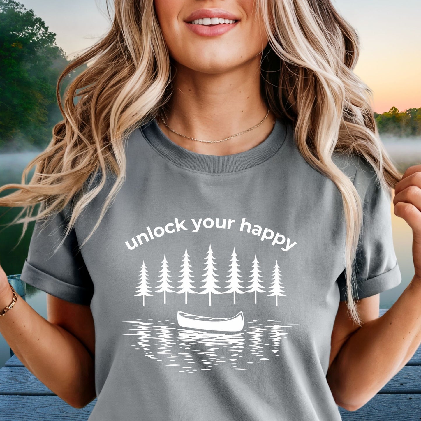 Woman wearing a gray t-shirt with nature-themed  canoe design and unlock your happy text.