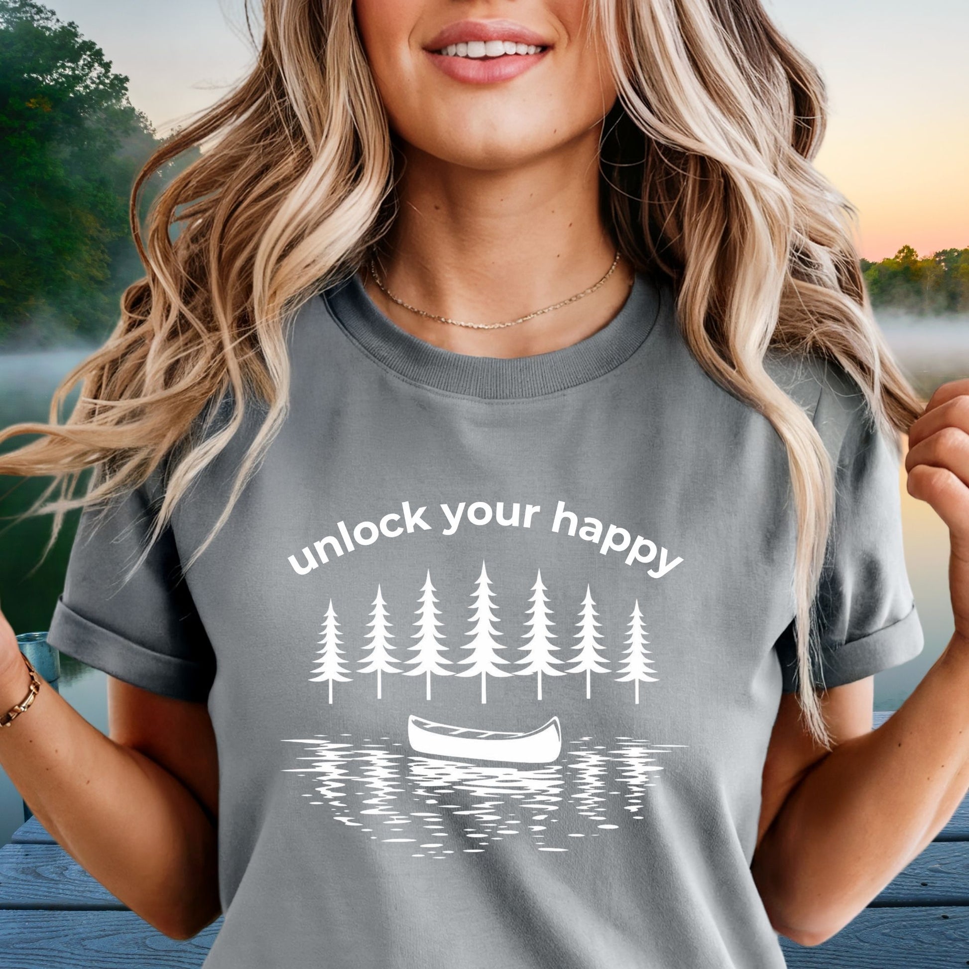 Woman wearing a gray t-shirt with nature-themed  canoe design and unlock your happy text.