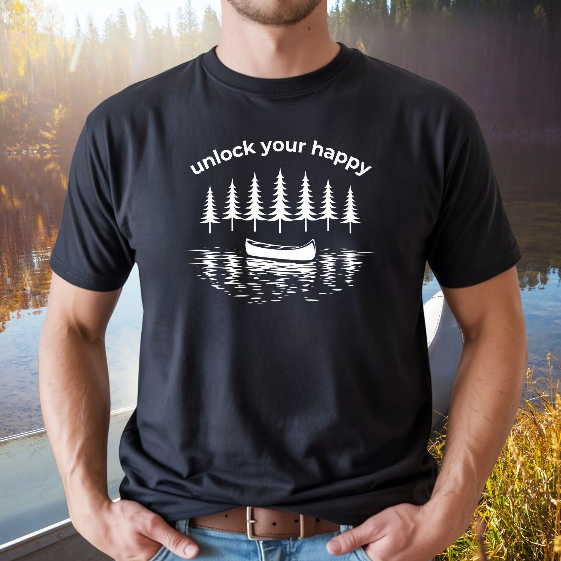 Person wearing a black t-shirt with a nature-themed canoe design and text unlock your happy.