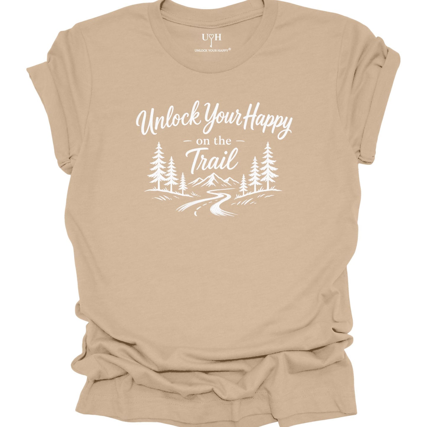 A tan short-sleeve t-shirt with a white graphic print that reads 'Unlock Your Happy on the Trail' above a simple forest and trail illustration. The shirt is shown flat against a white background, with the collar label reading 'UYH".