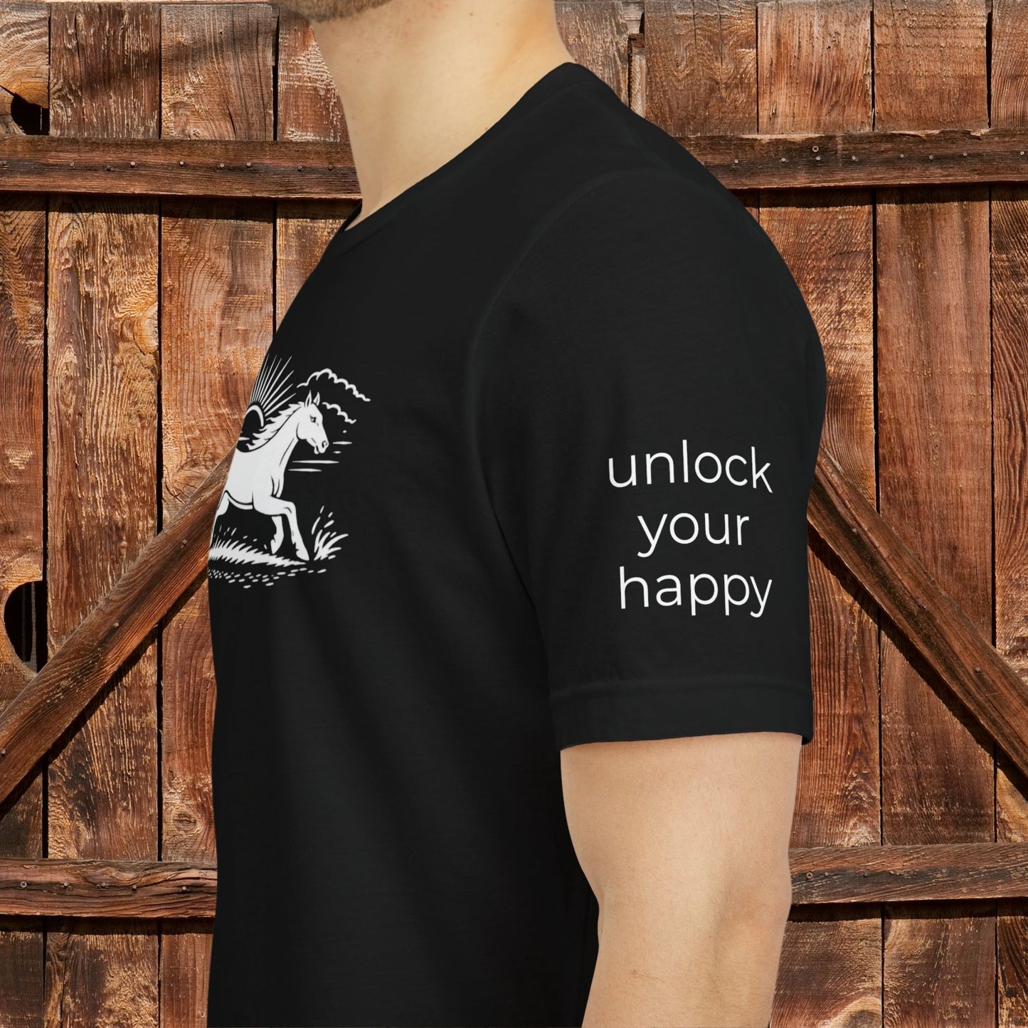Black t-shirt with 'unlock your happy' text on the sleeve, worn by a person against a wooden background.