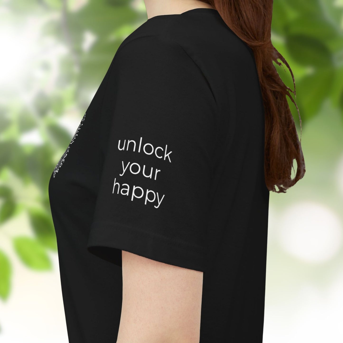 Person wearing a black t-shirt with 'unlock your happy' text on the sleeve, standing in a natural setting.
