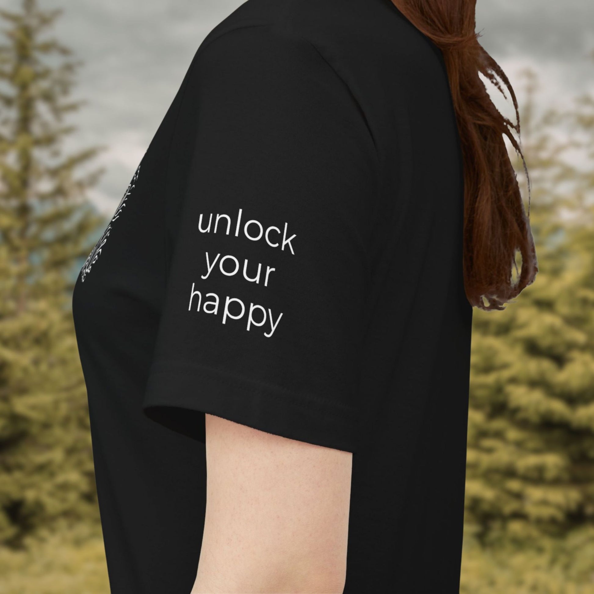 Person wearing a black shirt with 'unlock your happy' text on sleeve, standing outdoors.