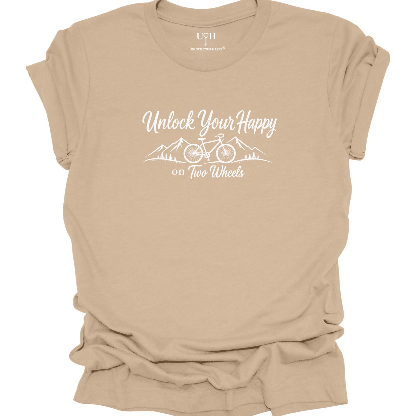 A tan short-sleeve t-shirt with a white graphic print that reads 'Unlock Your Happy on Two Wheels' with a bicycle and mountain illustration, shown on a plain white background.